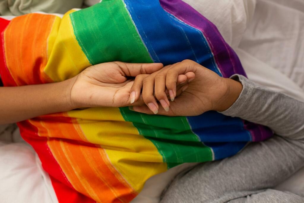 Two hands held together over a rainbow blanket